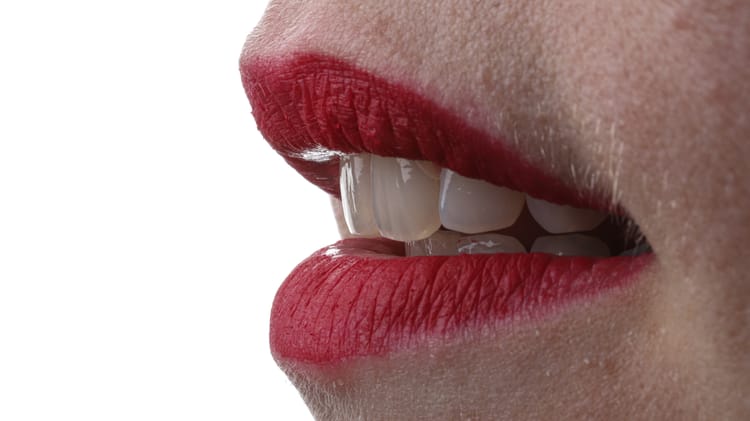 Detailaufnahme eines lächelnden Mundes mit roten Lippen und gut ausgeleuchteten Zähnen – Beispiel für Bildschärfe in der Dentalfotografie.